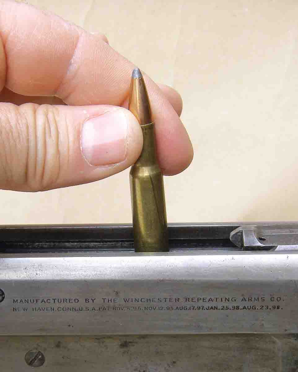 To load the single-stack magazine in the Winchester Model 1895, cartridges are inserted with the rim down, then tilted forward and laid into the lips of the magazine.